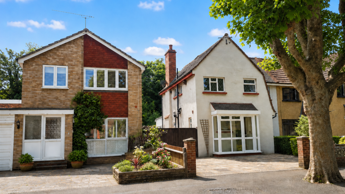 Two houses on a sunny suburban street with a large tree on the right and small front gardens.